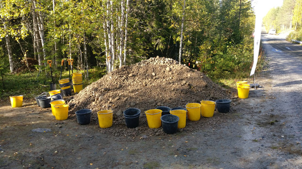 Sankkoja, lapioita ja soraa joilla täyttää veden pohjaa